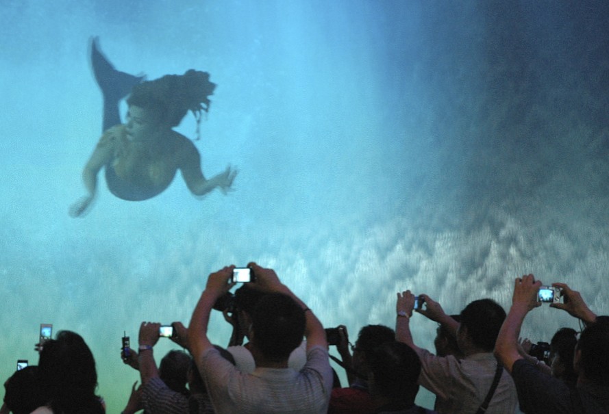 Tourists taking pictures of a projected mermaid image in one of Macao’s luxury entertainment and consumption hubs.